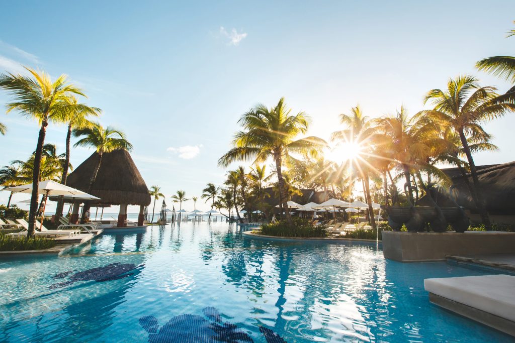 Resort tropical con piscina rodeado de palmeras junto al mar